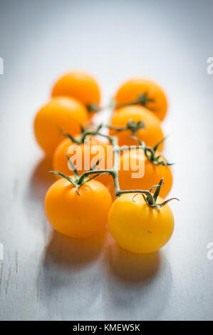 Pomodori giallo sulla vite su sfondo di legno Foto Stock