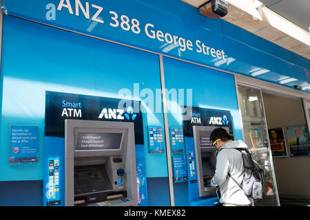 Maschio asiatici tramite bancomat ATM presso una filiale della banca ANZ in George Street, centro di Sydney, Australia Foto Stock