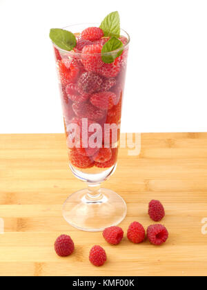 Bicchiere d'acqua pieno con lamponi isolati su tavola in legno Foto Stock