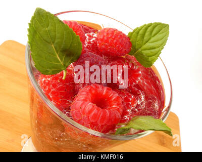 Bicchiere d'acqua pieno con lamponi isolati su tavola in legno Foto Stock