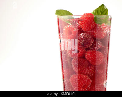 Bicchiere d'acqua pieno con lamponi isolati su tavola in legno Foto Stock