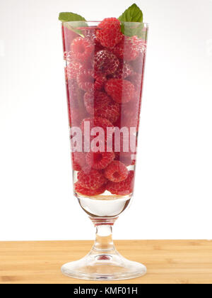 Bicchiere d'acqua pieno con lamponi isolati su tavola in legno Foto Stock