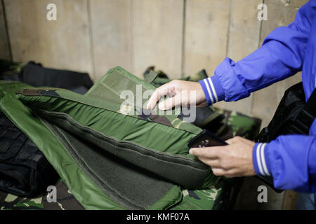 Un uomo sta ispezionando un antiproiettile giubbotto militare Foto Stock