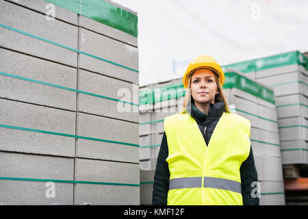 Lavoratore di sesso femminile in piedi in una zona industriale. Foto Stock