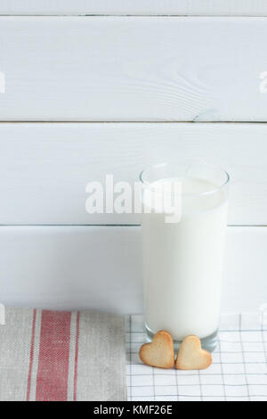 Biscotti sotto forma di cuori con latte su sfondo tessile. Foto Stock