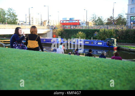 Asian Girls rilassanti in autunno il sole sulle rive di Regents Canal, sulle merci in modo, a Kings Cross, London, England, Regno Unito Foto Stock