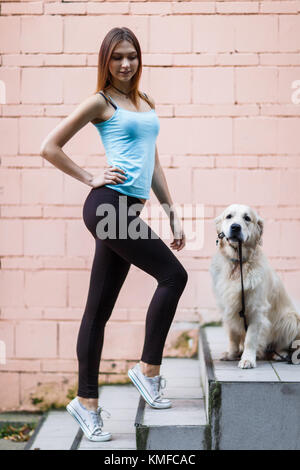 Foto di sport brunette con labrador in prossimità della parete edilizia Foto Stock