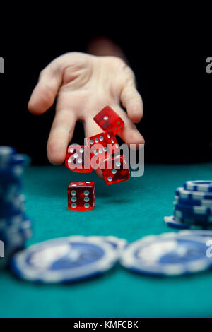 Foto di un uomo gettando dadi rossi sulla tavola con chip nel casinò Foto Stock