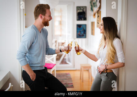 Coppia felice di bere birra e tostatura a casa Foto Stock