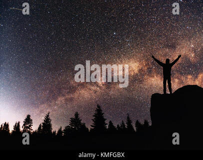 Silhouette giovane uomo sullo sfondo della via lattea su una stella luminosa dark sky tono. Foto Stock