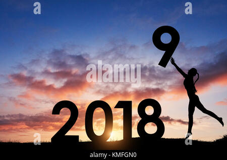 Silhouette della ragazza che contiene i numeri del nuovo anno al tramonto. Concetto di sostituzione 2018 al 2019. Foto Stock