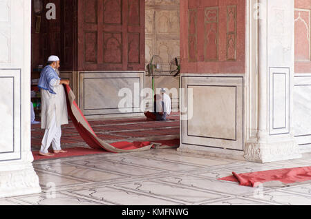 DELHI, India - 2 Maggio 2015: un uomo si sta diffondendo i tappeti, appena prima della preghiera di mezzogiorno nella principale sala di preghiera della Jama Masjid moschea, a Delhi, India Foto Stock