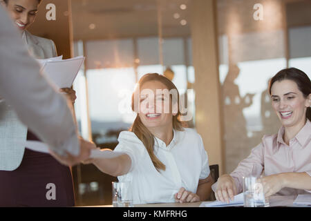 Sorridente imprenditrice di consegnare la documentazione a un collega in sala conferenza incontro Foto Stock