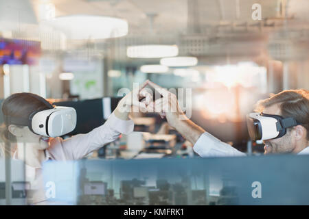 Programmatori di computer utilizzando la realtà virtuale occhiali simulatore, toccando le dita in office Foto Stock