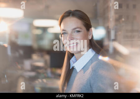 Ritratto sorridente, fiduciosi imprenditrice che indossa la cuffia in office Foto Stock