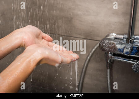 Gocce d'acqua che cadono in mani femminili Foto Stock