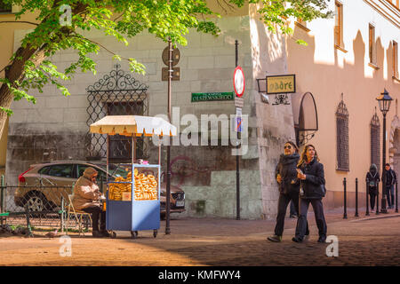 Città vecchia di Cracovia, vista di due donne maturo turisti passeggiando davanti a un pretzel stand in una piazza nel quartiere della città vecchia (stare Miasto) di Cracovia, Polonia Foto Stock