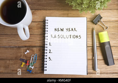 Anno nuovo risoluzioni sul blocco note con tazza di caffè e delle forniture di ufficio. Foto Stock