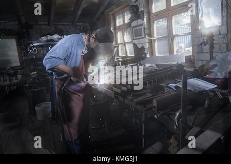 Fabbro fondendo cancello giardino in officina Foto Stock