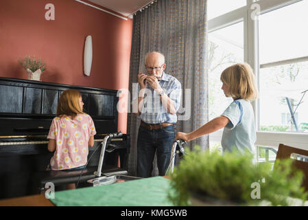 Nonno che suona strumento musicale con i bambini Foto Stock