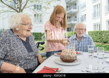 Famiglia che festeggia il compleanno della nonna nel cortile di casa di riposo Foto Stock