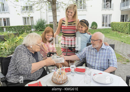 Famiglia che festeggia il compleanno della nonna nel cortile di casa di riposo Foto Stock