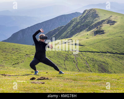 Donna che pratica il karate si muove con i vetri di realtà virtuale sulla montagna Foto Stock