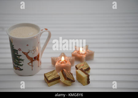 Natale immagine di fotografia con spumeggiante bevanda calda in renna boccale per stampa a caldo con candele e lusso alimentare al cioccolato bianco su uno sfondo di legno Foto Stock