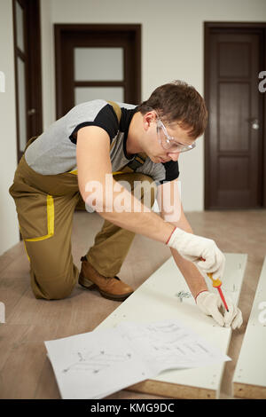 Uomo di installare le viti nella porta di legno. professionale tema carpenter Foto Stock