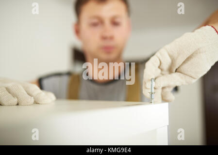 Macro di mettere la vite in mobili con uomo sfocata in background Foto Stock