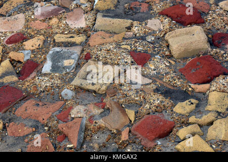 Una selezione di diversi pezzi di rotture di mattoni di edificio, pietre e materiali impostato in alcuni concreti in un modello casuale per formare un percorso di astratta. Foto Stock