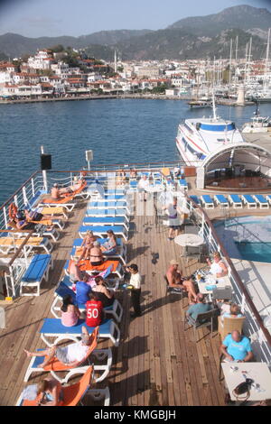 La Turchia, Alanya, nave da crociera per vacanza rilassante sul ponte durante il passaggio dalla zona costiera con faro , barche , case, e le montagne. Foto Stock