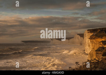 Birling Gap, East Sussex, Regno Unito 7 dicembre 2017..Sun attraversa le nuvole illuminando le scogliere di gesso delle sette Sorelle mentre le estremità meridionali della Storm Caroline frusta il surf. Foto Stock