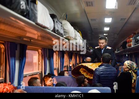 (171209) -- URUMQI, 9 dicembre 2017 (Xinhua) -- un assistente aiuta i passeggeri con bagagli sul treno n. 5809 che collega Kashgar e Hotan nella regione autonoma Xinjiang Uygur della Cina nord-occidentale, 24 novembre 2017. Il percorso ferroviario di 485 km che collega due grandi città oasi Kashgar e Hotan, attraversa alcune delle aree più remote dello Xinjiang e ha trasformato la vita nel deserto dal suo lancio nel 2011. È la prima e unica ferrovia di Hotan, attraverso la ferrovia la prefettura sottosviluppata è collegata al resto della rete ferroviaria del paese, che vanta 22.000 km di linee ferroviarie ad alta velocità. Scarsa tra Foto Stock