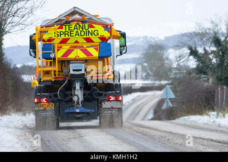 Flintshire, Galles, 9 dicembre 2017. Regno Unito Meteo. Con una Met Office avviso di colore giallo per la neve di oggi e di domani ambra che è una minaccia per la vita, Flintshire County Council spazzaneve e gritters si lotta per mantenere le strade per il prossimo 36ore. Un Snow Plough gritter e affrontare le strade rurali nel villaggio di Lixwm in Flintshire con coperte di neve gamma Clwydian nella distanza © DGDImages/Alamy Live News Foto Stock