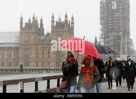 Londra, Regno Unito. Decimo Dec, 2017. La gente a piedi nella neve sul Westminster Bridge nel centro di Londra, Gran Bretagna a Dic. 10, 2017. Credito: Han Yan/Xinhua/Alamy Live News Foto Stock