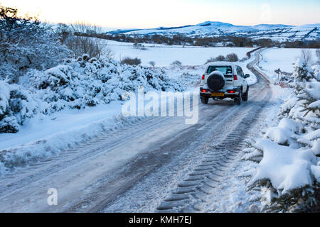 Flintshire, Nord, Regno Unito. Regno Unito Meteo. Con una Met Office avviso di colore giallo per condizioni di gelo per molti oggi. Pendolari si scia fino a un hard-neve e ghiaccio nero e di ciò che la stampa sta chiamando "Black Monday". Un driver di affrontare con cautela la neve ghiacciata coperto le strade rurali vicino al villaggio di Moel-y-Crio, Flintshire con la gamma Clwydian nella distanza Foto Stock