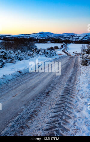 Flintshire, Nord, Regno Unito Meteo. Con una Met Office avviso di colore giallo per condizioni di gelo per molti oggi. Pendolari si scia fino a un hard-neve e ghiaccio nero e di ciò che la stampa sta chiamando "Black Monday". Treaturous condizioni stradali con Nero ghiaccio e neve vicino al villaggio di Moel-y-Crio con la gamma Clwydian nella distanza di sunrise Foto Stock