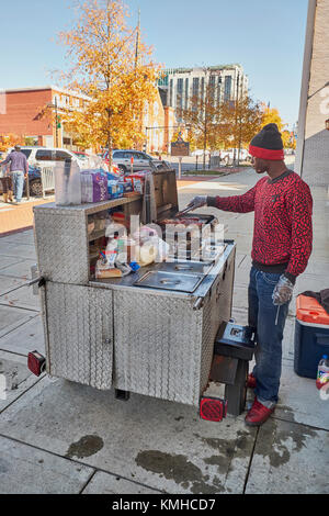 Maschio nero, americano africano, vendono hotdog dal suo carrello su un marciapiede in città. Foto Stock