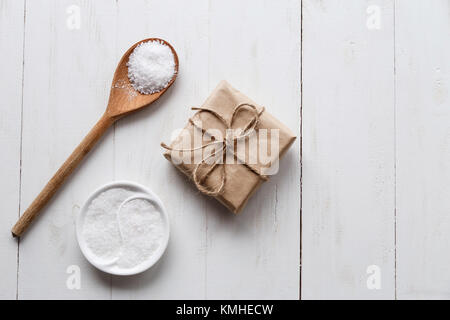 Un sano sale marino con giftbox bianco su sfondo di legno. Lay piatto. Copia dello spazio. Foto Stock