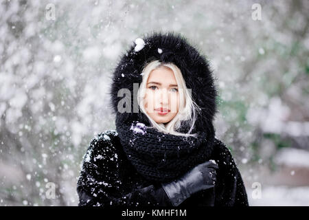 Ritratto della bella ragazza bionda in una calda pelliccia outdoor in una foresta innevata. Foto Stock