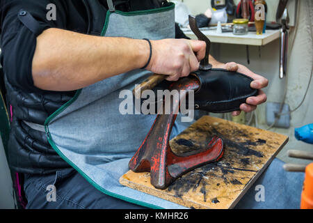 Calzolaio riparazione di una suola per calzature in officina. Messa a fuoco selettiva. Vintage Foto Stock