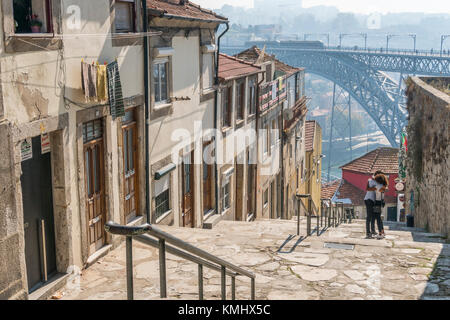 Le fasi che conducono in basso verso il fiume Douro lungomare nel quartiere Ribeira di Porto, Portogallo. con il Dom Luis I Bridge in background. Foto Stock