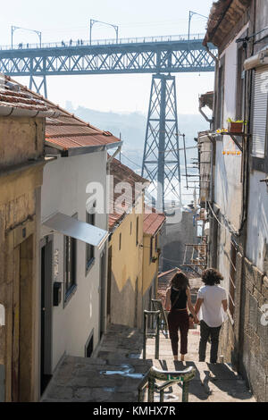 Le fasi che conducono in basso verso il fiume Douro lungomare nel quartiere Ribeira di Porto, Portogallo. con il Dom Luis I Bridge in background. Foto Stock