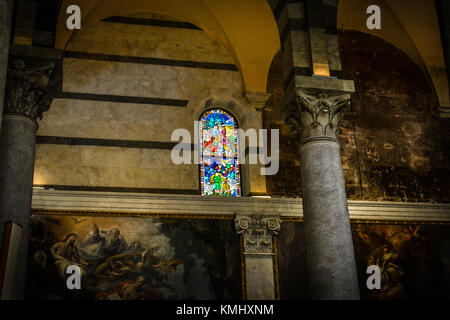 Piccola finestra di vetro colorato circondato da dipinti rinascimentali su una parete interna del Duomo di Pisa in Italia Foto Stock