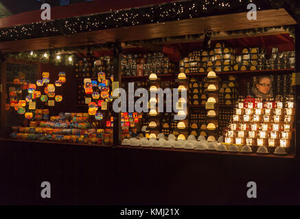 Una giovane donna produttore presso il suo mercatino di Natale in stallo la vendita di una varietà di portacandele. Parte di Edimburgo di Natale a George Square nel west end Foto Stock