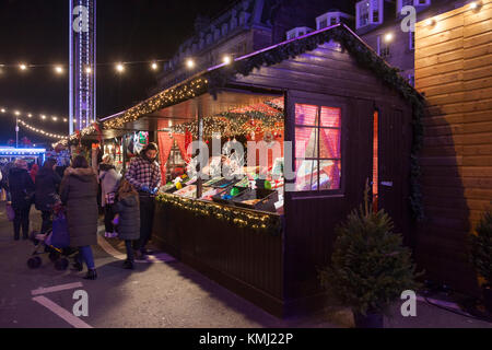 Il fornitore e i pedoni a una novità di stallo dolciari: Mercatino di Natale di George Street di Edimburgo di Natale 2017. Un regalo in stallo è adiacente Foto Stock