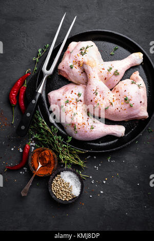 Il pollo crudo quarti, gambe in una padella su uno sfondo scuro. Vista dall'alto. Foto Stock