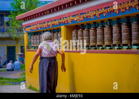 Pokhara, Nepal - 06 ottobre 2017: unidentified vecchia donna pilgrin toccando la ruota pregando nel tempio tibetano, padum, kashmir india Foto Stock