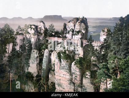 Il Bastei è una formazione rocciosa situata nelle montagne di arenaria dell'Elba in Germania. È famosa per la sua incredibile bellezza naturale e il suo significato storico, in particolare per il suo iconico ponte che collega diverse vette e offre vedute panoramiche del paesaggio circostante. Foto Stock